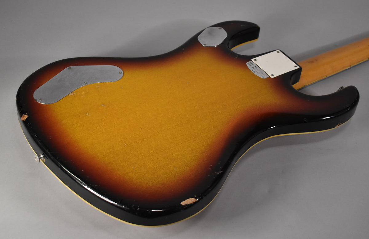 The guitar's sunburst back shows two metal control plates, a neck plate, and significant finish wear and chips along the edges.
