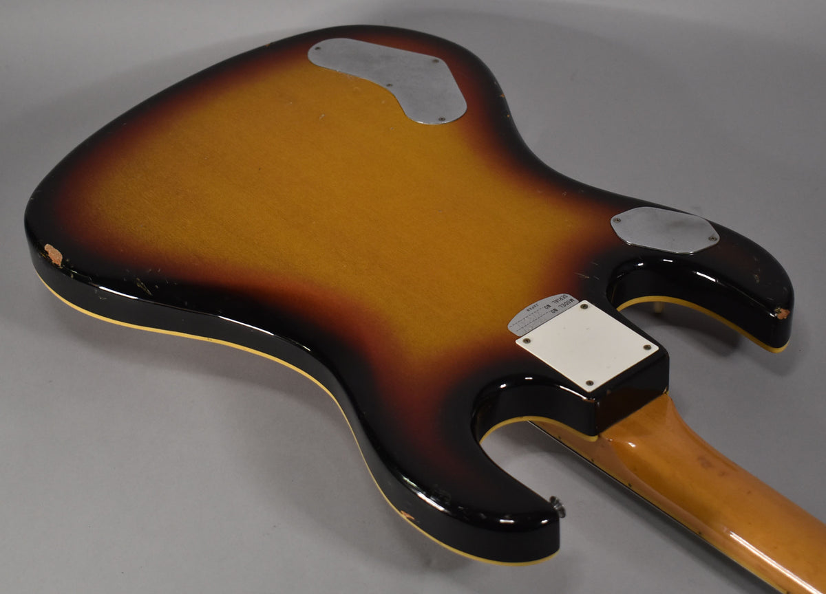 The guitar's sunburst back shows wear, with two chrome control plates and a white neck plate, plus a strap button.