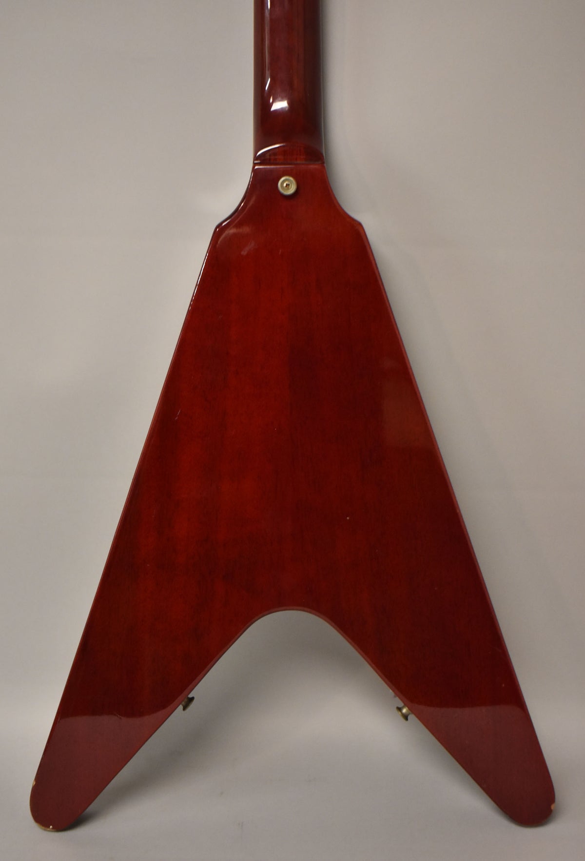 Rear view of a cherry red Flying V guitar, showing the neck joint and body with a few small dings on the lower right wing.