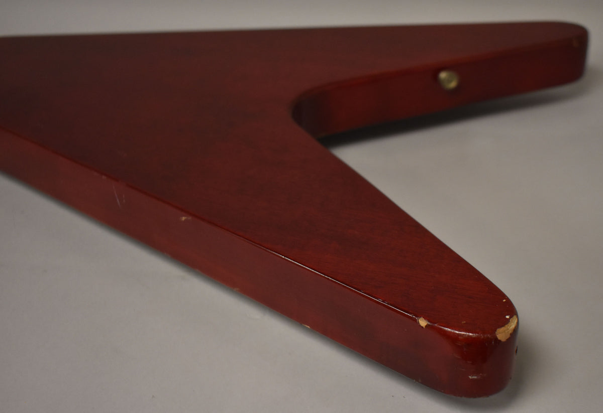 Close-up of the cherry red Flying V body, showing the lower wing tip with significant finish chips and a few surface scratches.