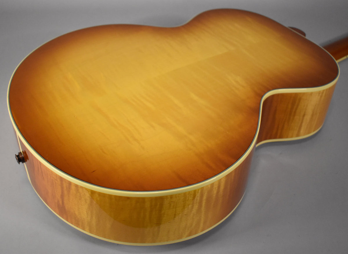 The guitar's back and sides, in a cherry sunburst finish with visible wood grain, are shown from a high angle.
