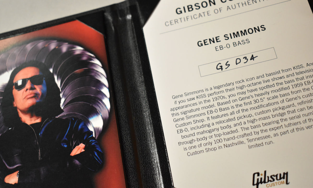 A close-up of a black leather folder, with a photo of Gene Simmons on the left and a white certificate of authenticity on the right.