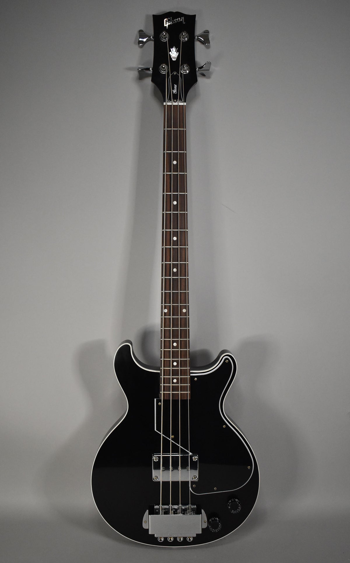 Full front view of a glossy black bass with white binding, a large chrome bridge, and a black pickguard.