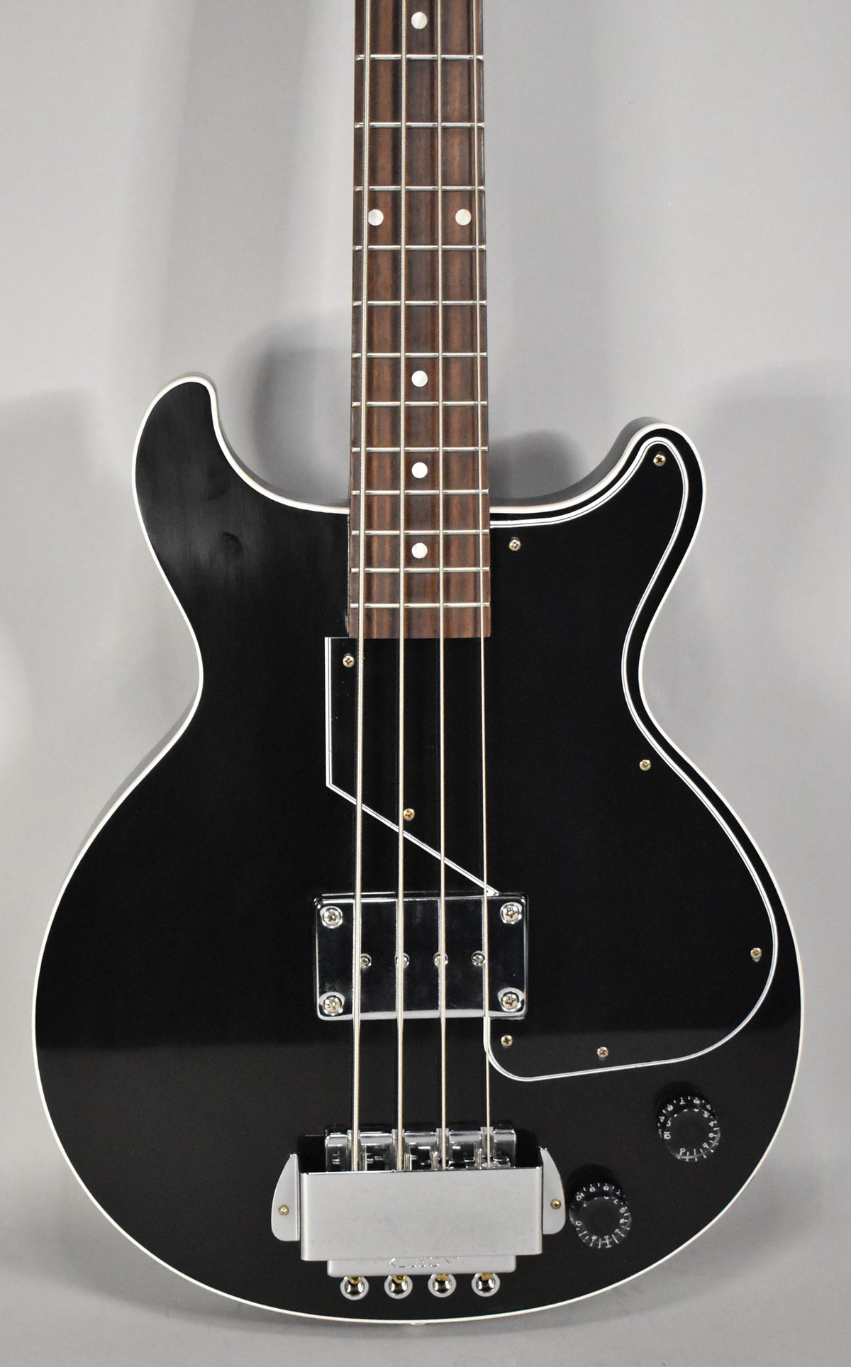 The black bass guitar is shown from the upper body to the bridge, featuring a single chrome pickup, bridge cover, and two control knobs.