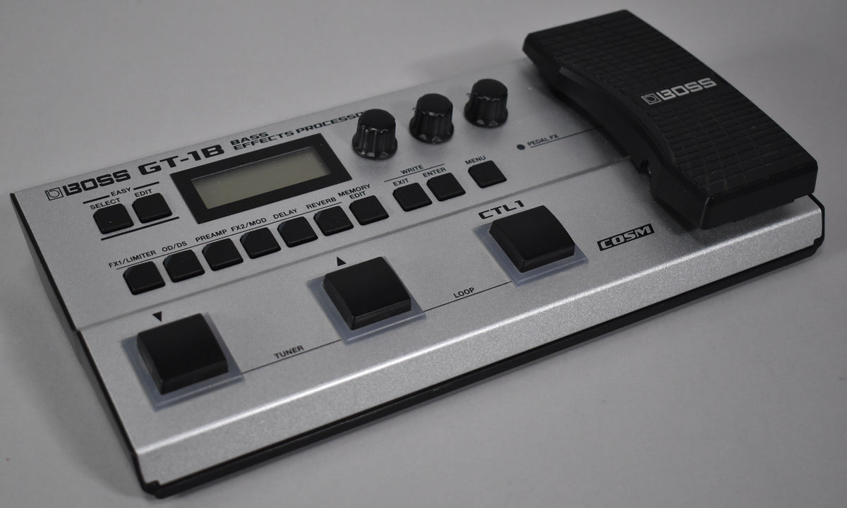 A silver multi-effects pedal with a black expression pedal on the right, a small screen, three black knobs, and many black buttons.