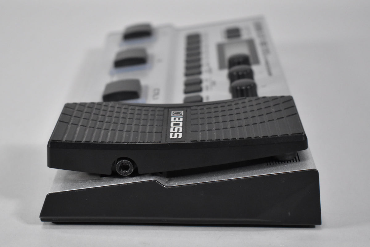The multi-effect pedal is angled from the left, showing its black textured expression pedal and silver base with black side panels.
