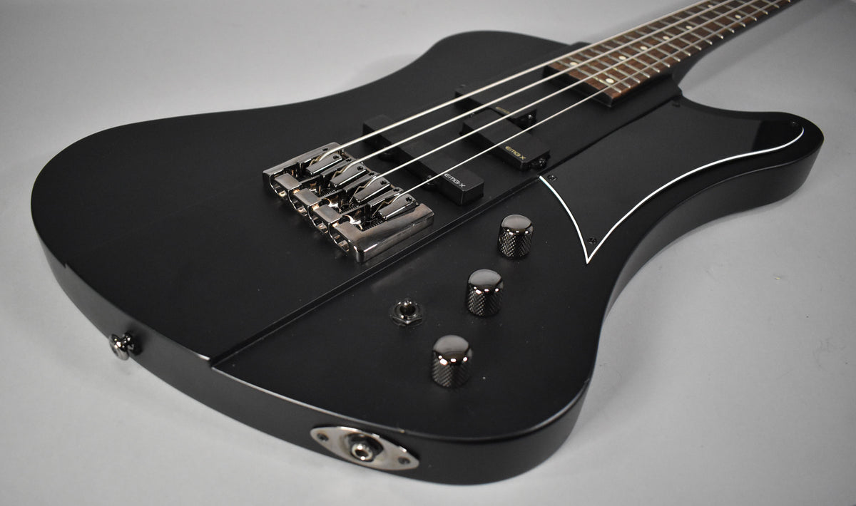The satin black bass body, angled from the lower right, features a chrome bridge, two pickups, three knurled knobs, and a white-bound pickguard.