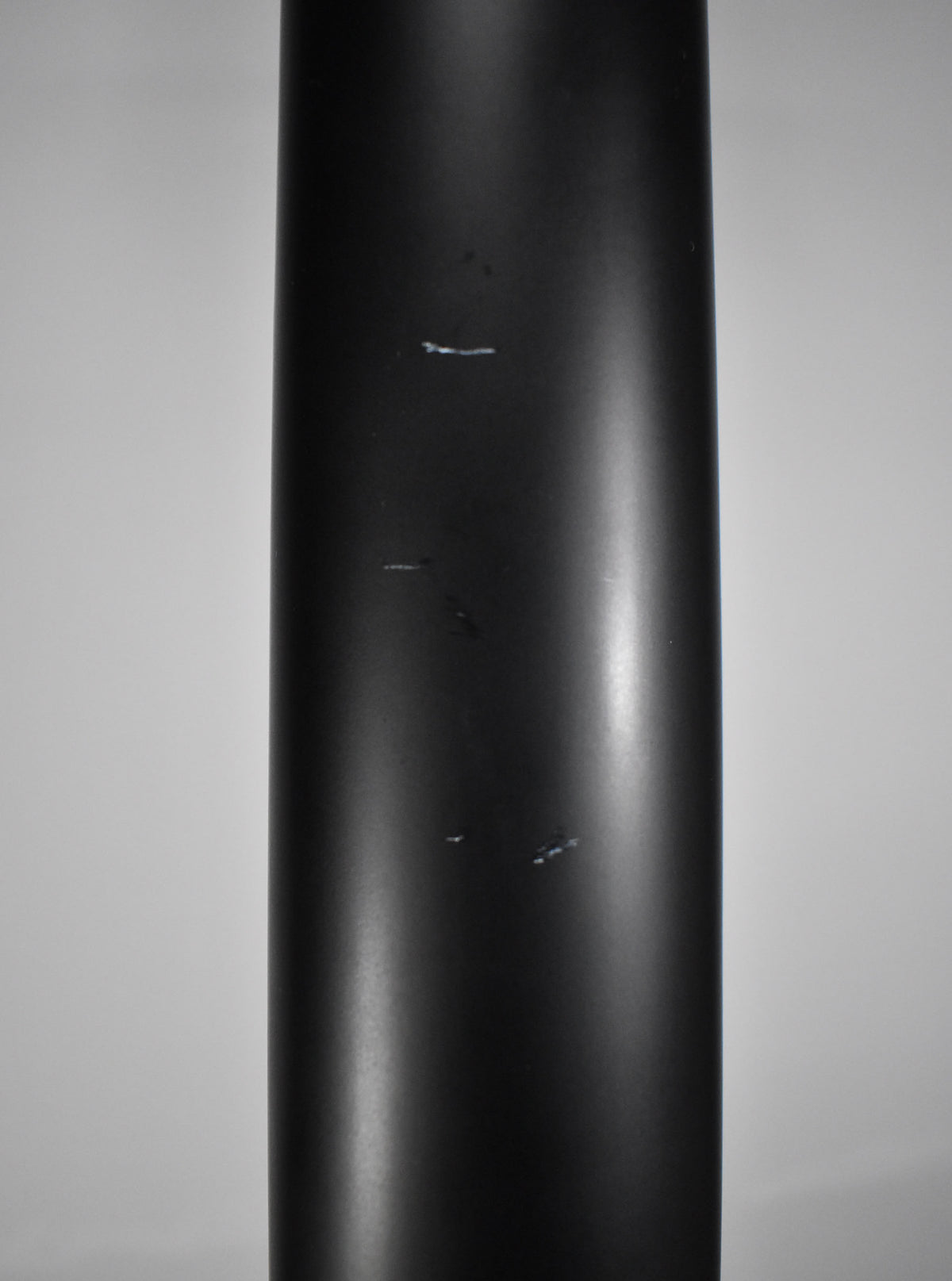 Close-up of the satin black bass neck, showing several small white scuffs and scratches on the matte finish.