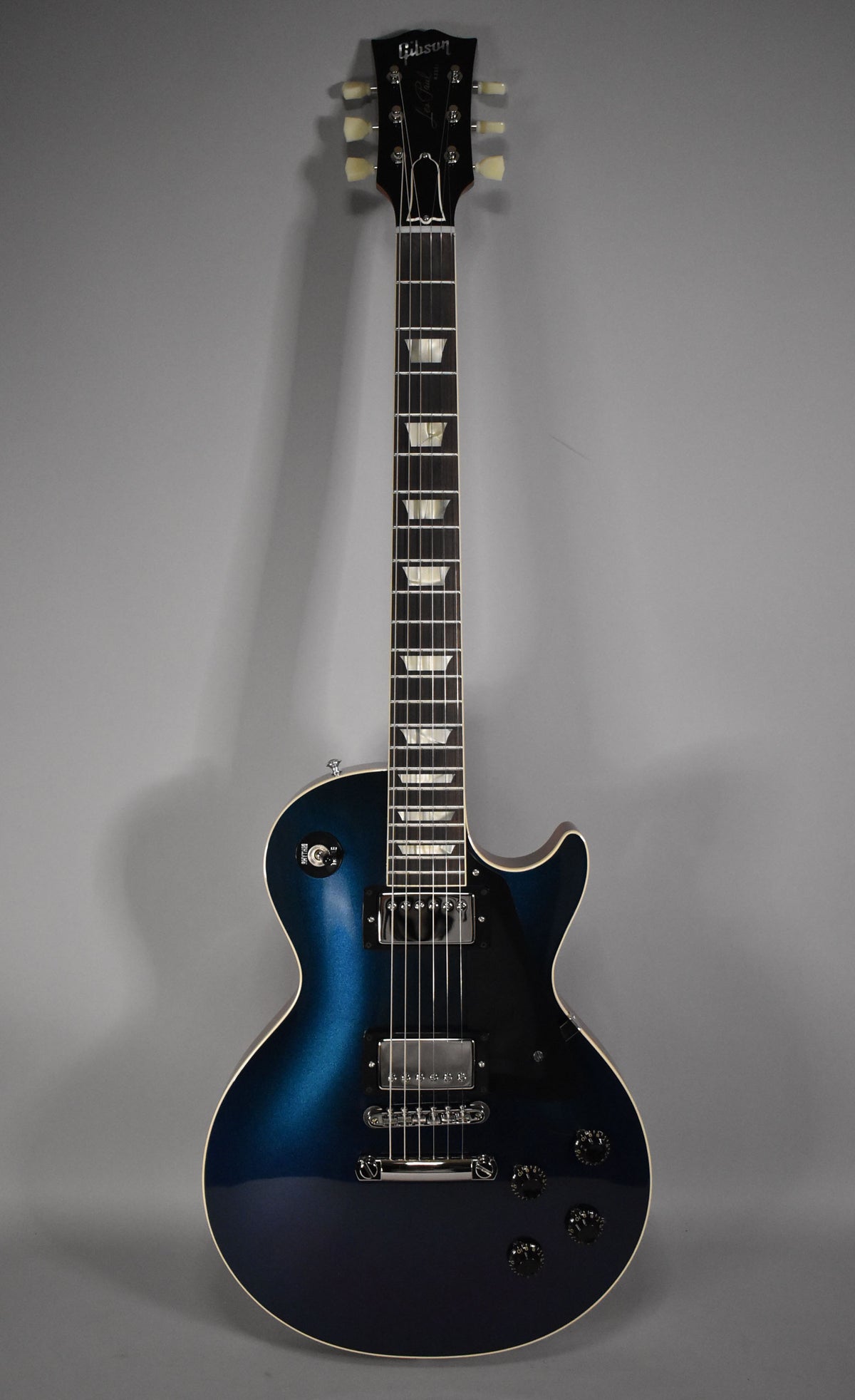 Full-length view of a blue-to-black burst Les Paul with cream binding, black pickguard, chrome hardware, and trapezoid inlays.