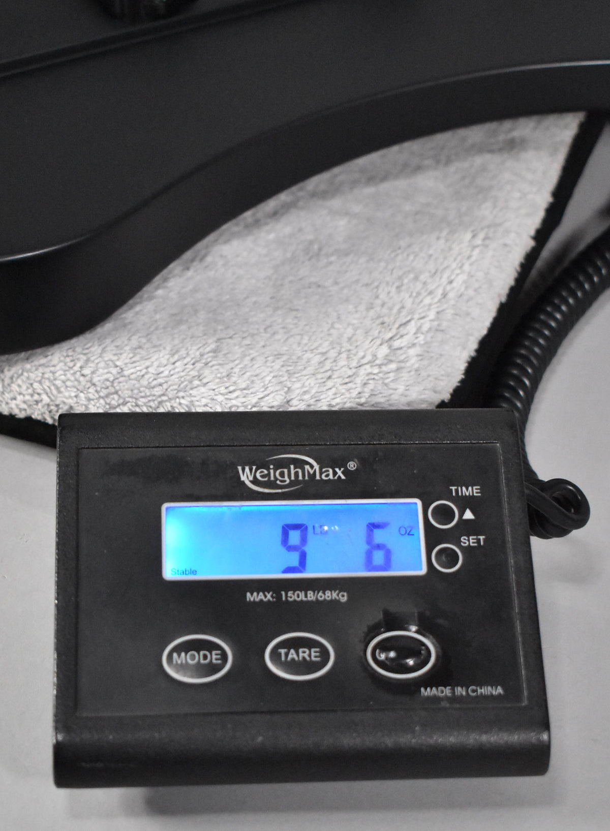 A digital scale displays "9 Lb 6 Oz" with the bass's satin black body resting on a gray towel above it.