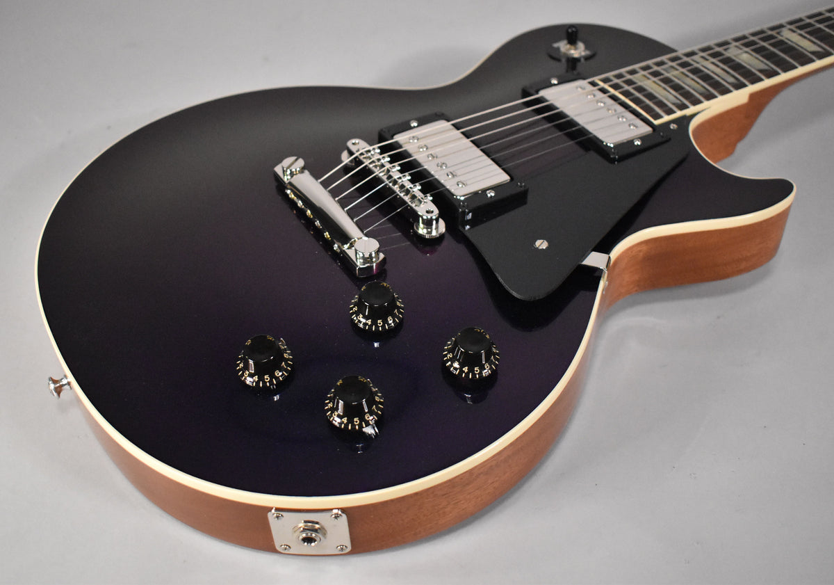 The Les Paul's dark purple top, with chrome hardware and black knobs, is framed from the lower bout to the neck pickup.
