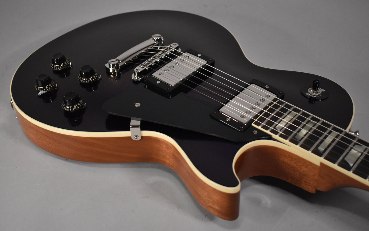 The guitar's dark blue top, with four black knobs and two chrome humbuckers, meets a natural wood side with cream binding.