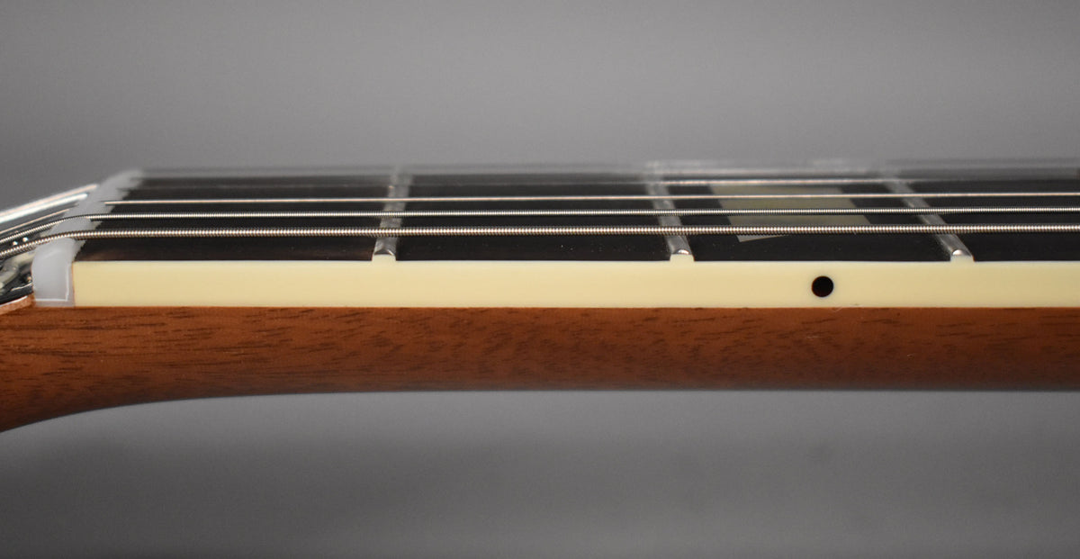 Close-up of the guitar's neck, showing the dark fretboard, cream binding, and a black side dot marker on the light brown neck wood.