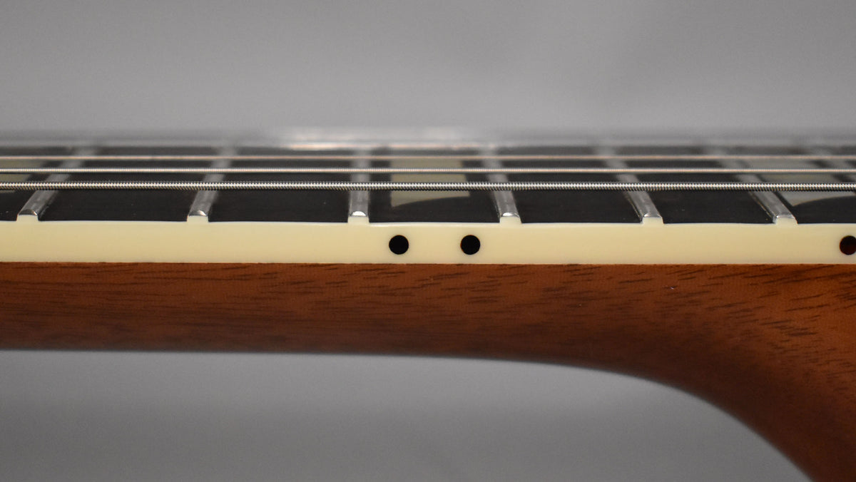 Close-up of the guitar's neck from the side, showing the dark fretboard, light binding, and two black side dot markers.
