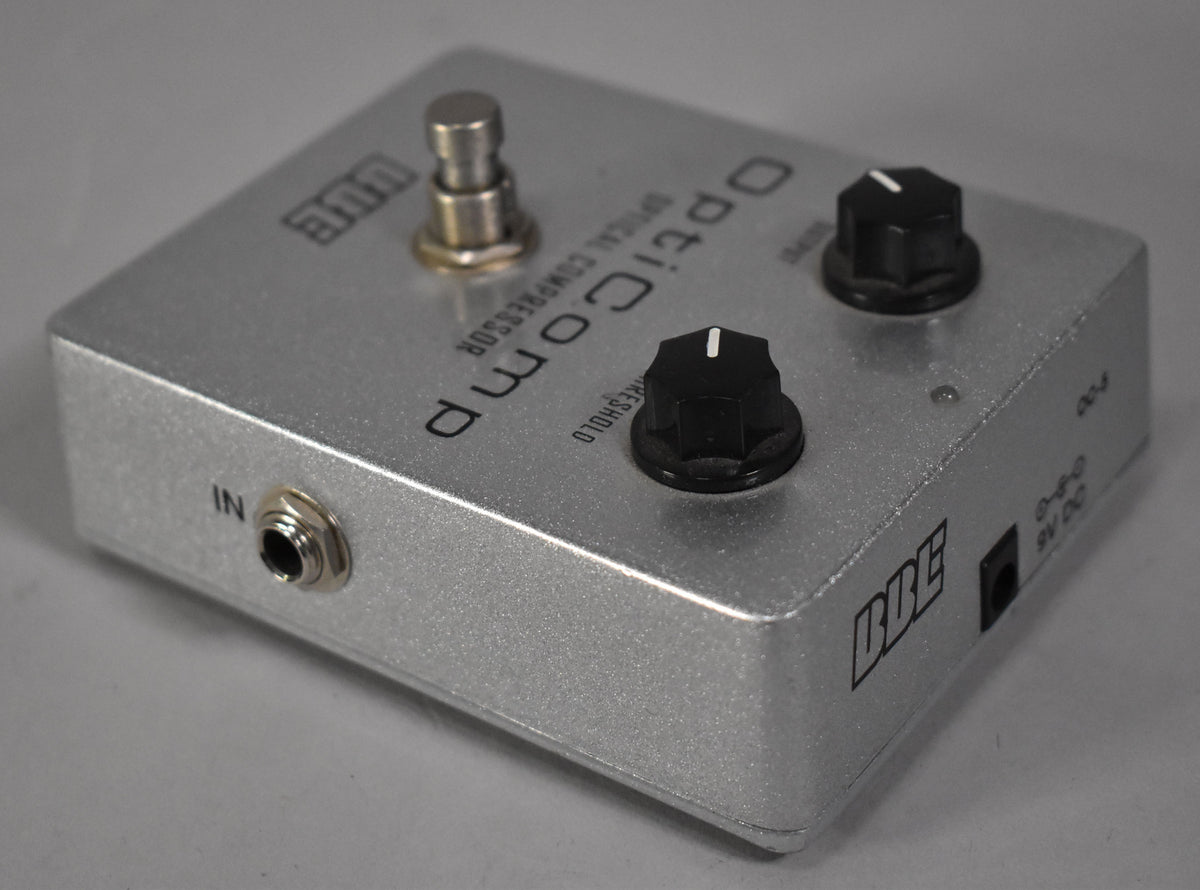 A silver guitar pedal, viewed from the front-left, with two black control knobs and a footswitch on top.