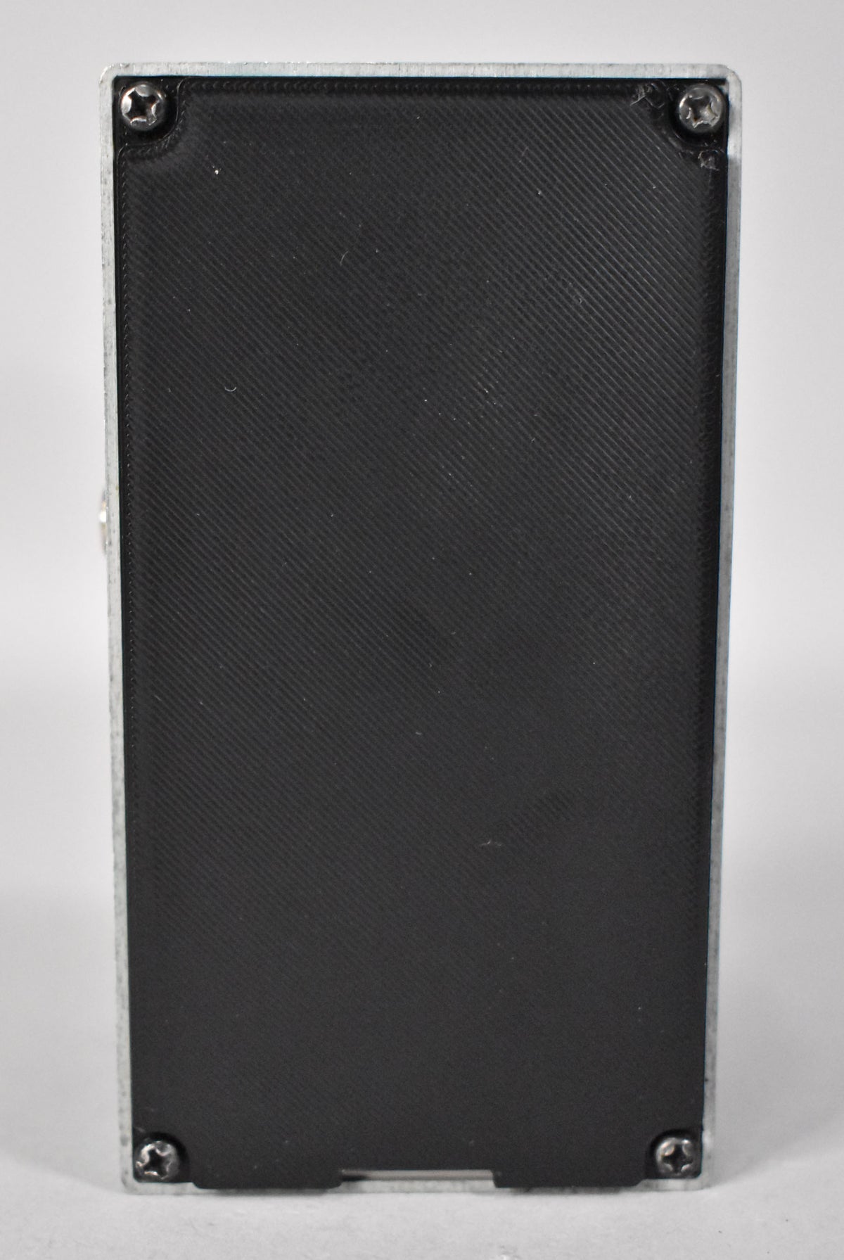 The pedal's black, diagonally ribbed base plate is secured by four silver Phillips head screws to a silver-painted metal chassis.