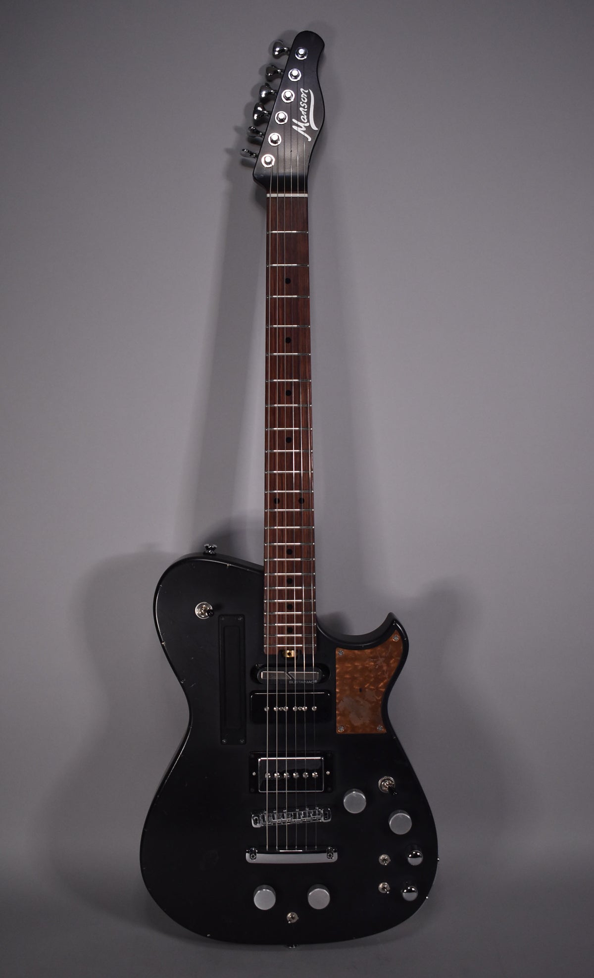 Full front view of a black relic electric guitar with a dark fretboard, two humbuckers, and a mottled brown pickguard.