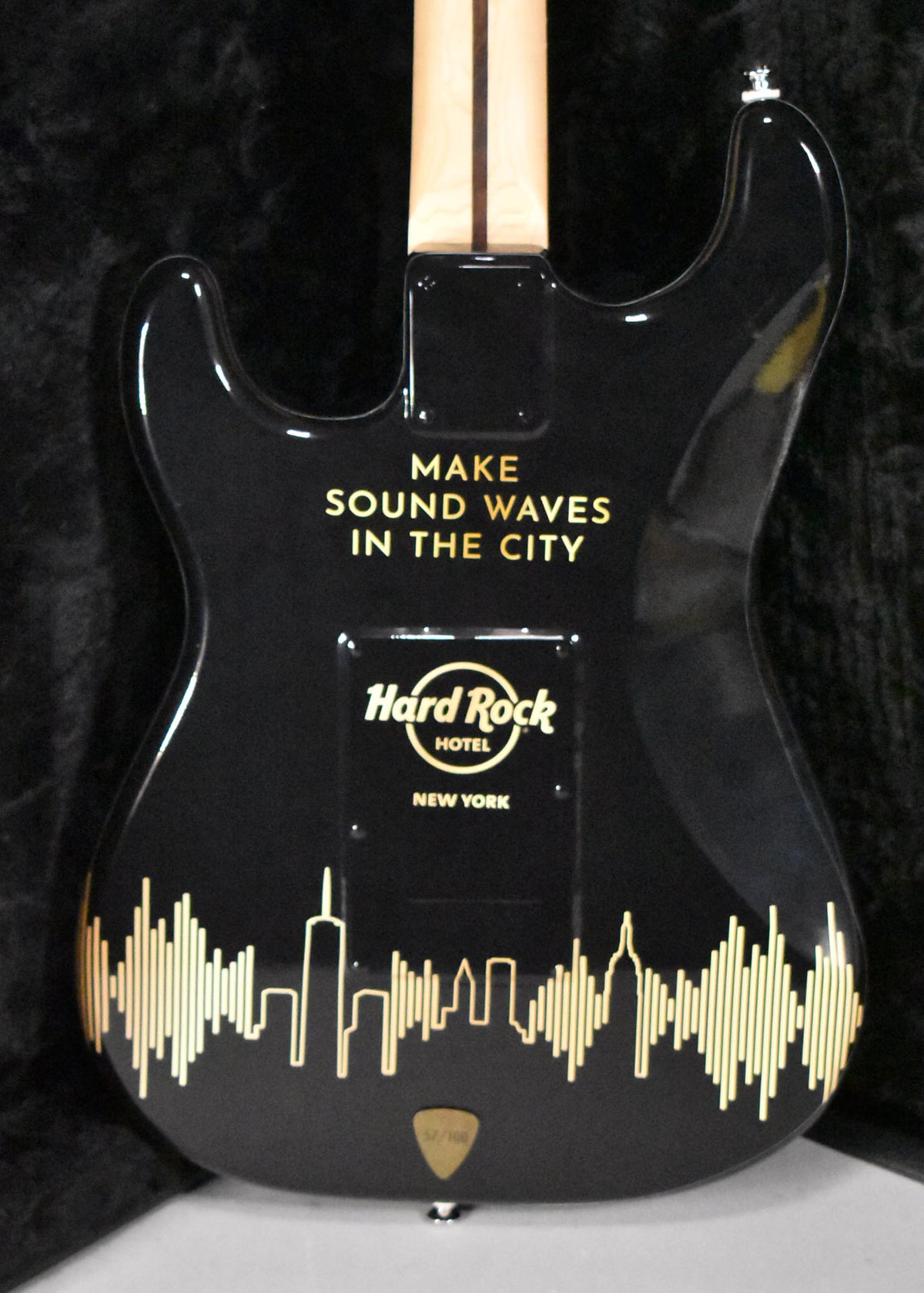 The guitar's glossy black back features gold "MAKE SOUND WAVES IN THE CITY" text, a Hard Rock Hotel logo, and a New York skyline graphic.
