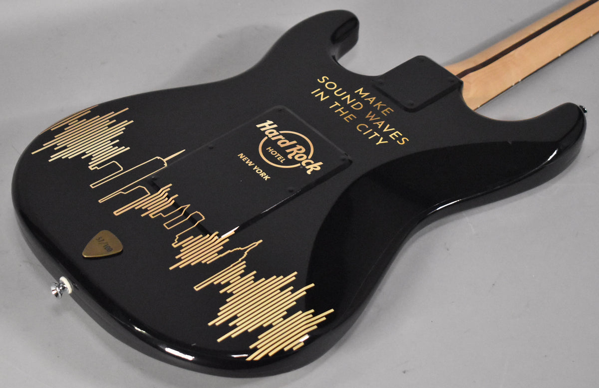 The black guitar body, viewed from the back, features gold Hard Rock Cafe NYC branding, a skyline, and sound wave graphics.