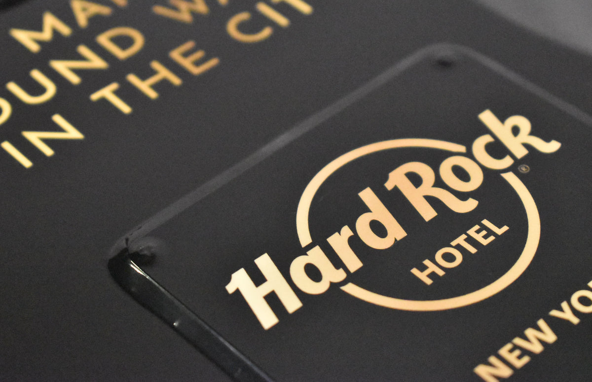 Close-up of the black hard shell case, showing a gold Hard Rock Hotel logo and partial gold lettering on the lid.