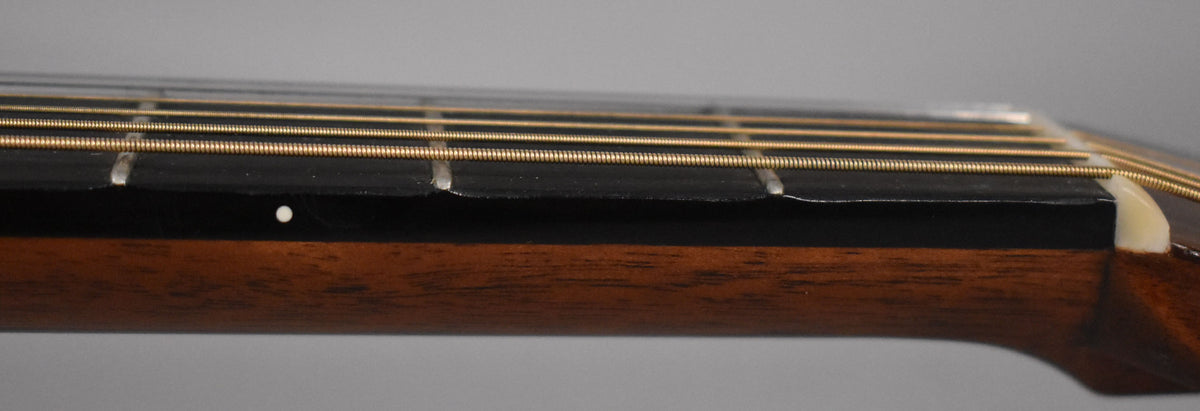 Close-up of the guitar's dark fretboard and brown neck, showing a white fret marker and some wear near the frets.