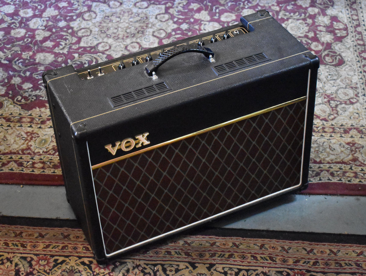 Black combo amp with gold piping, a diamond-patterned brown grille, and a black leather handle, viewed from the front-right.