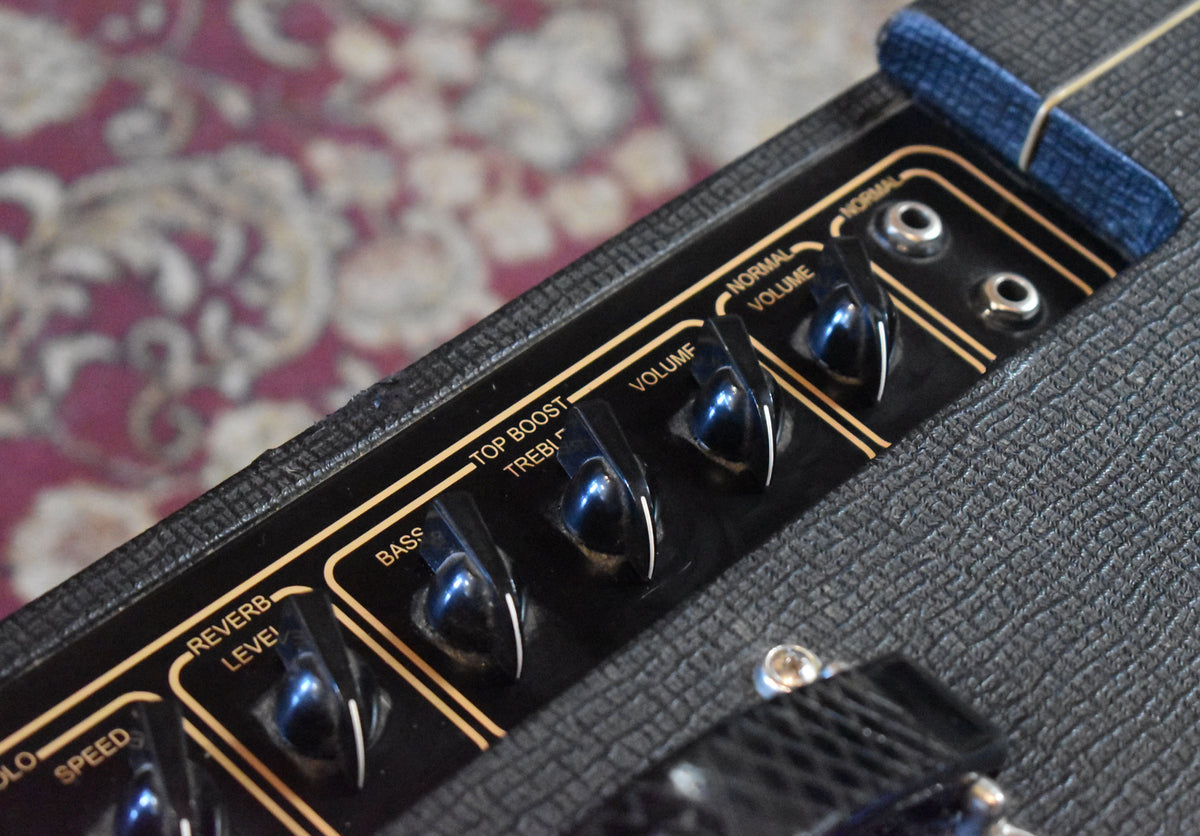 Close-up of the black control panel with gold lettering and black chicken-head knobs, showing "Reverb Level" to "Normal Volume" controls.