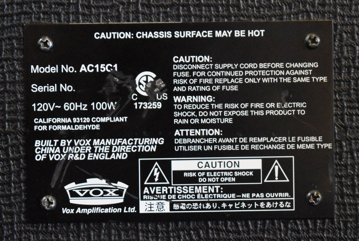 Close-up of the amplifier's black metal rear panel, showing white text for model number, serial number, and safety warnings.