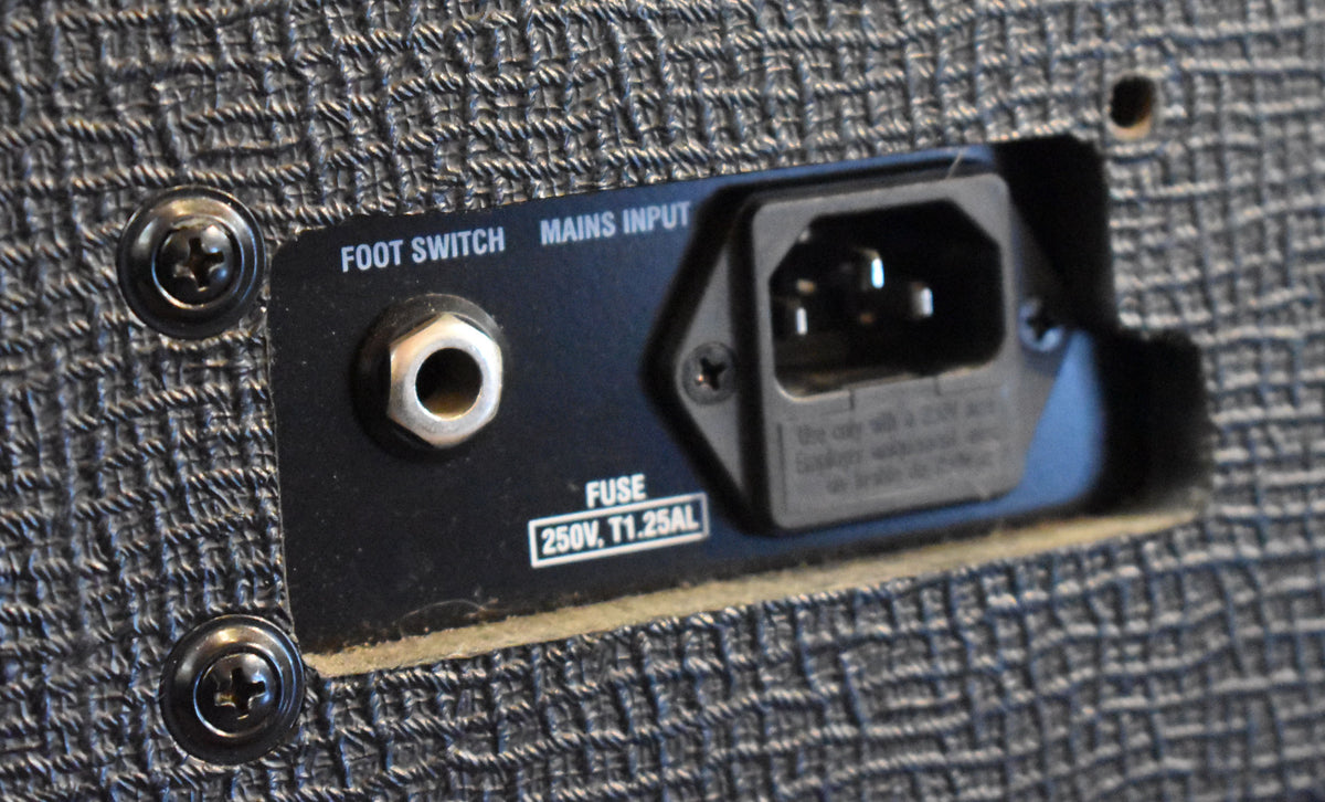 Close-up of the amp's black rear panel, showing the silver foot switch input jack and the mains input socket with fuse rating.