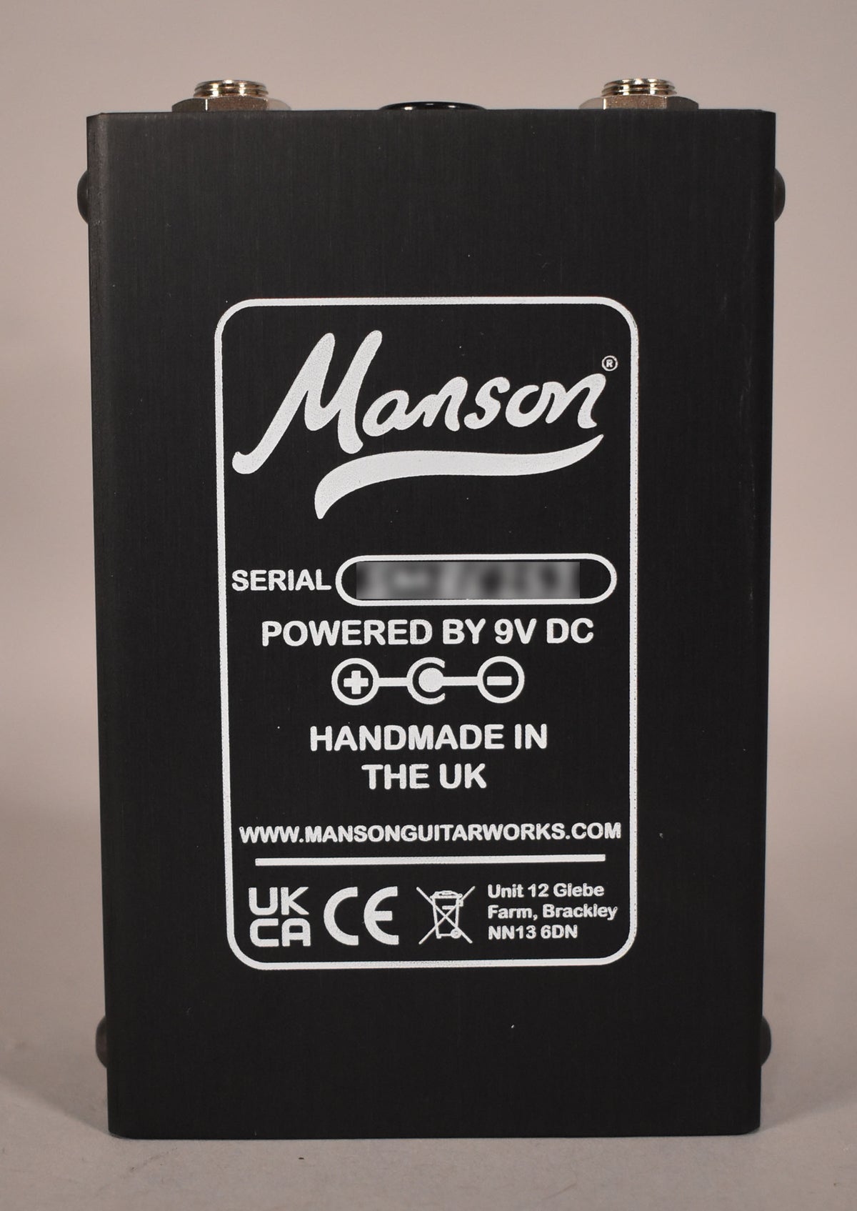 The black pedal's rear panel is shown, with white text indicating it is handmade in the UK and powered by 9V DC.