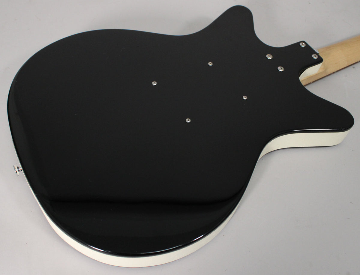 The guitar's glossy black back, with white binding, is angled from the lower bout to the neck joint, showing six neck screws.