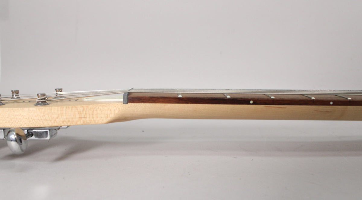 The guitar's light wood neck and dark fretboard are seen from the side, with silver tuning pegs visible on the left.