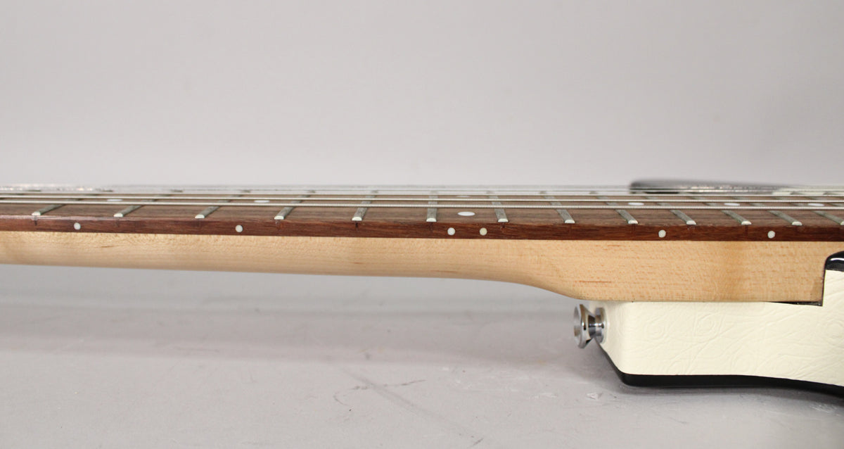 The guitar's neck and fretboard are viewed from the side, showing a light wood neck, dark fretboard with dot inlays, and white body binding.