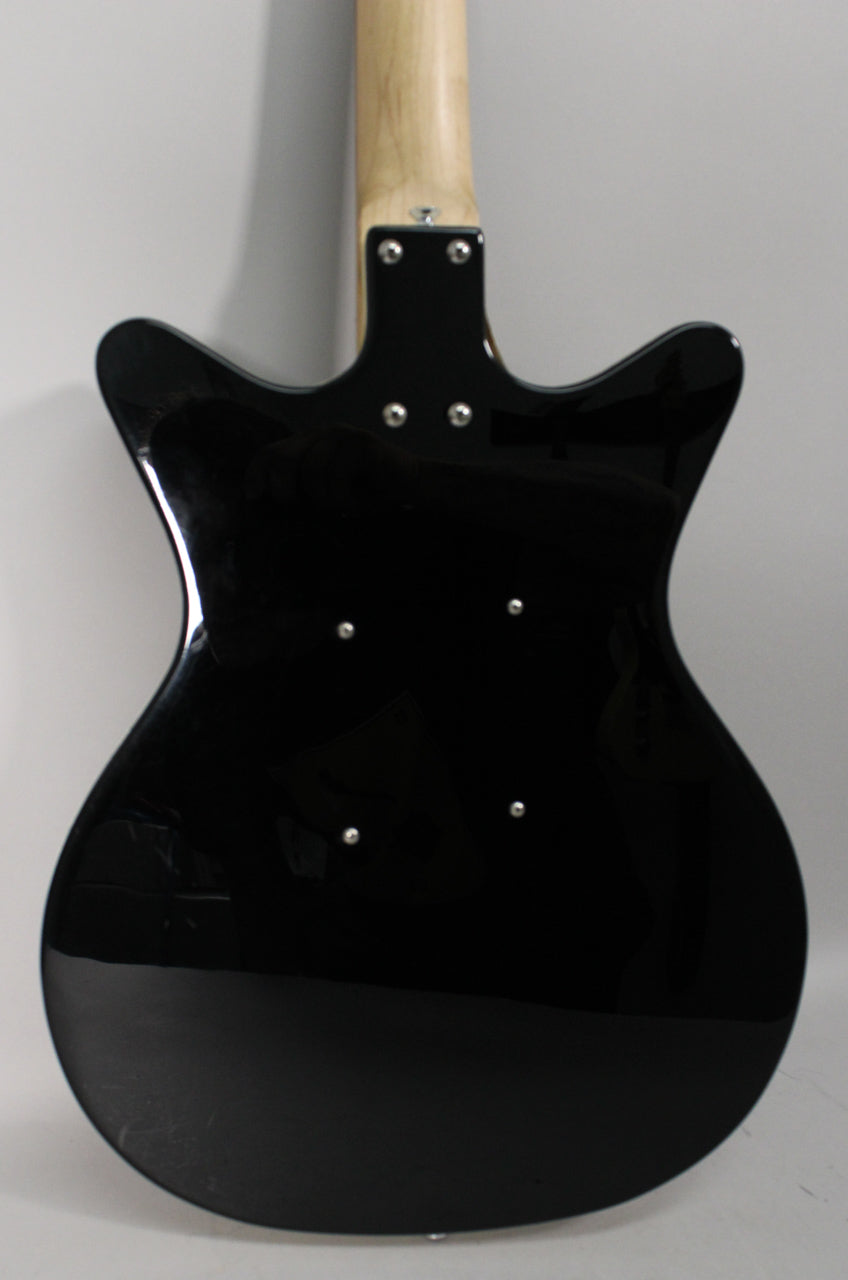 The back of the gloss black guitar body, showing a light wood neck, four neck bolts, and six small silver control access screws.