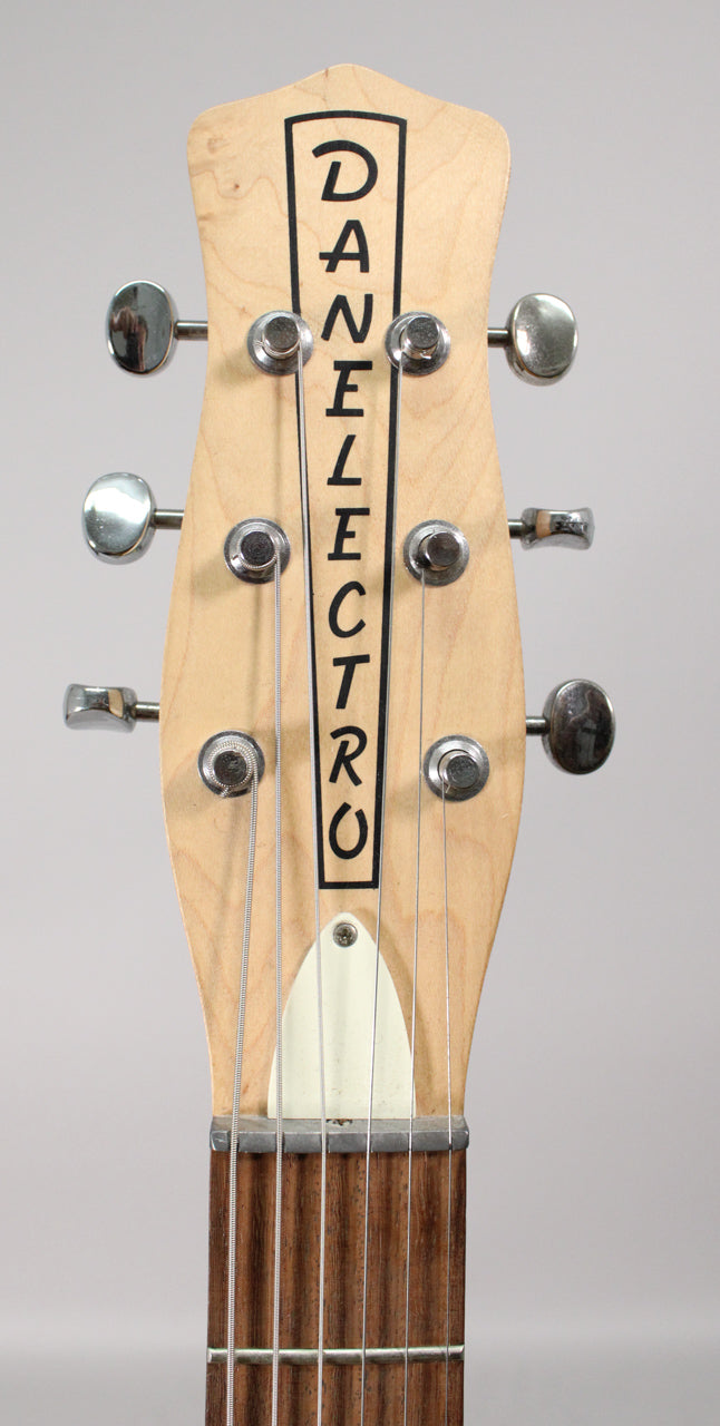 Close-up of the guitar's natural wood headstock with six chrome tuners, a white nut, and the top of the dark fretboard.