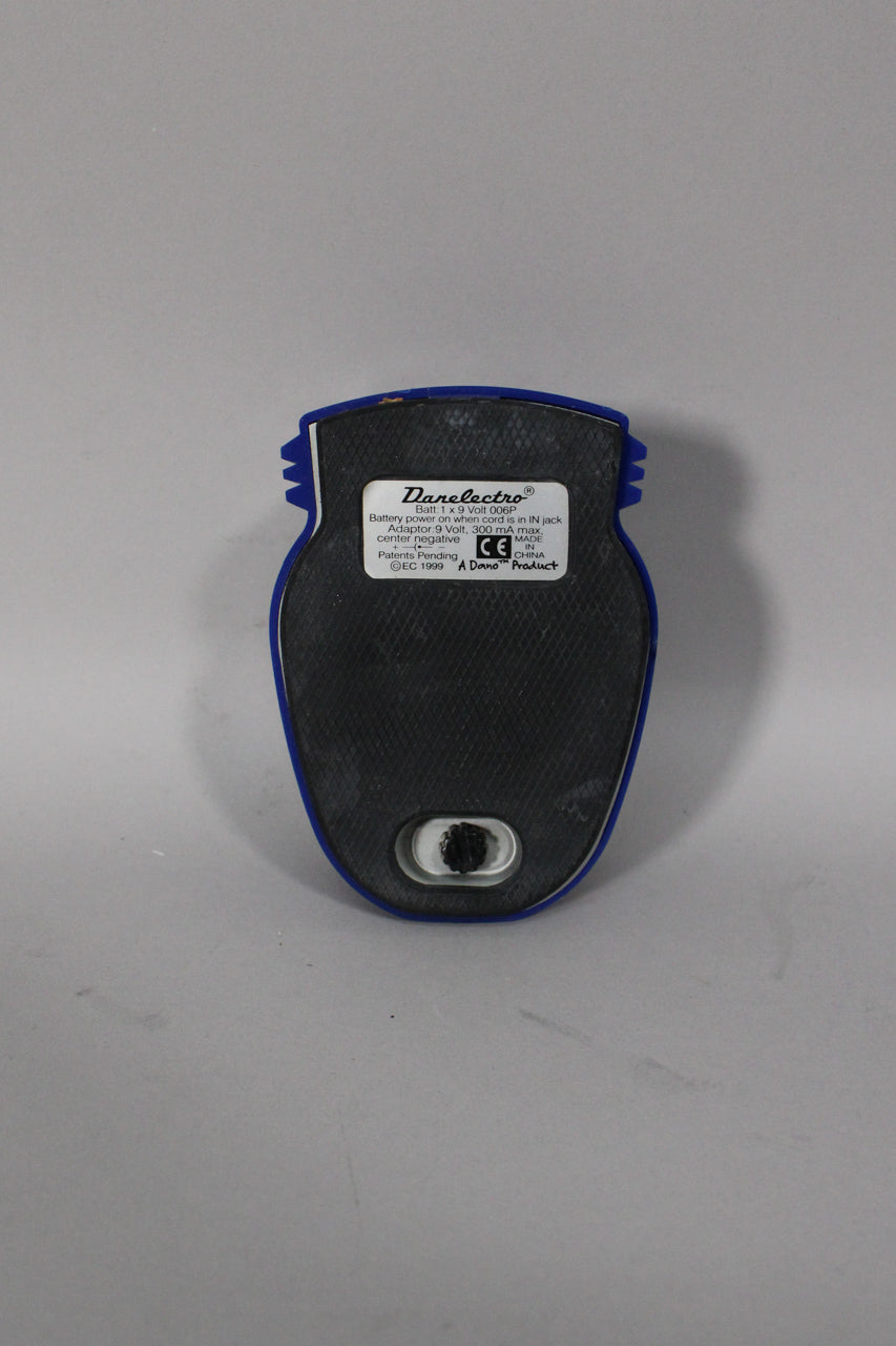 The pedal's blue plastic casing is seen from the back, revealing a black textured rubber base and a battery compartment.