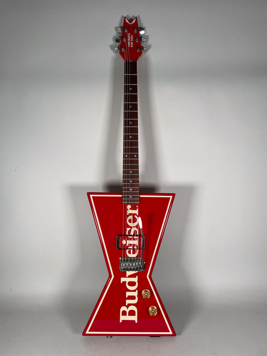 Full front view of a red bowtie-shaped guitar with white trim, a Floyd Rose tremolo, and two gold control knobs.
