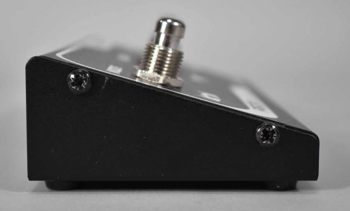 A close-up of the footswitch's textured black side panel, showing a silver footswitch and two black screws.