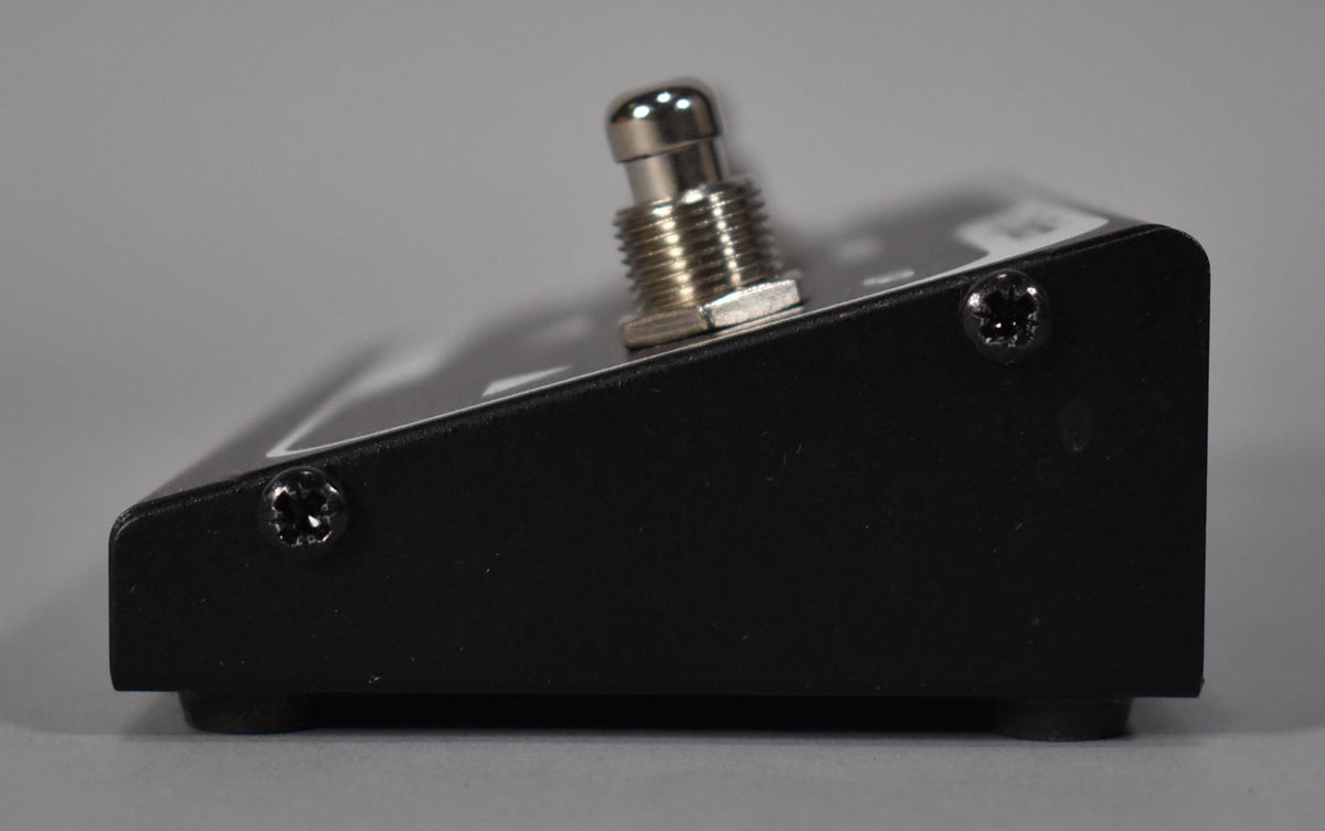 This side view shows the black pedal's slightly angled profile, with a single chrome footswitch and two black screws visible.