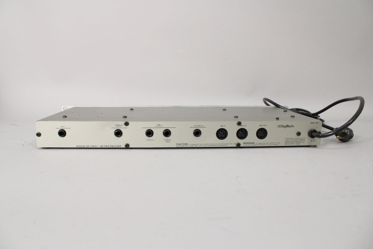 The rear of a light gray rackmount unit, showing various 1/4-inch and MIDI ports, with a black power cord coiled on the right.