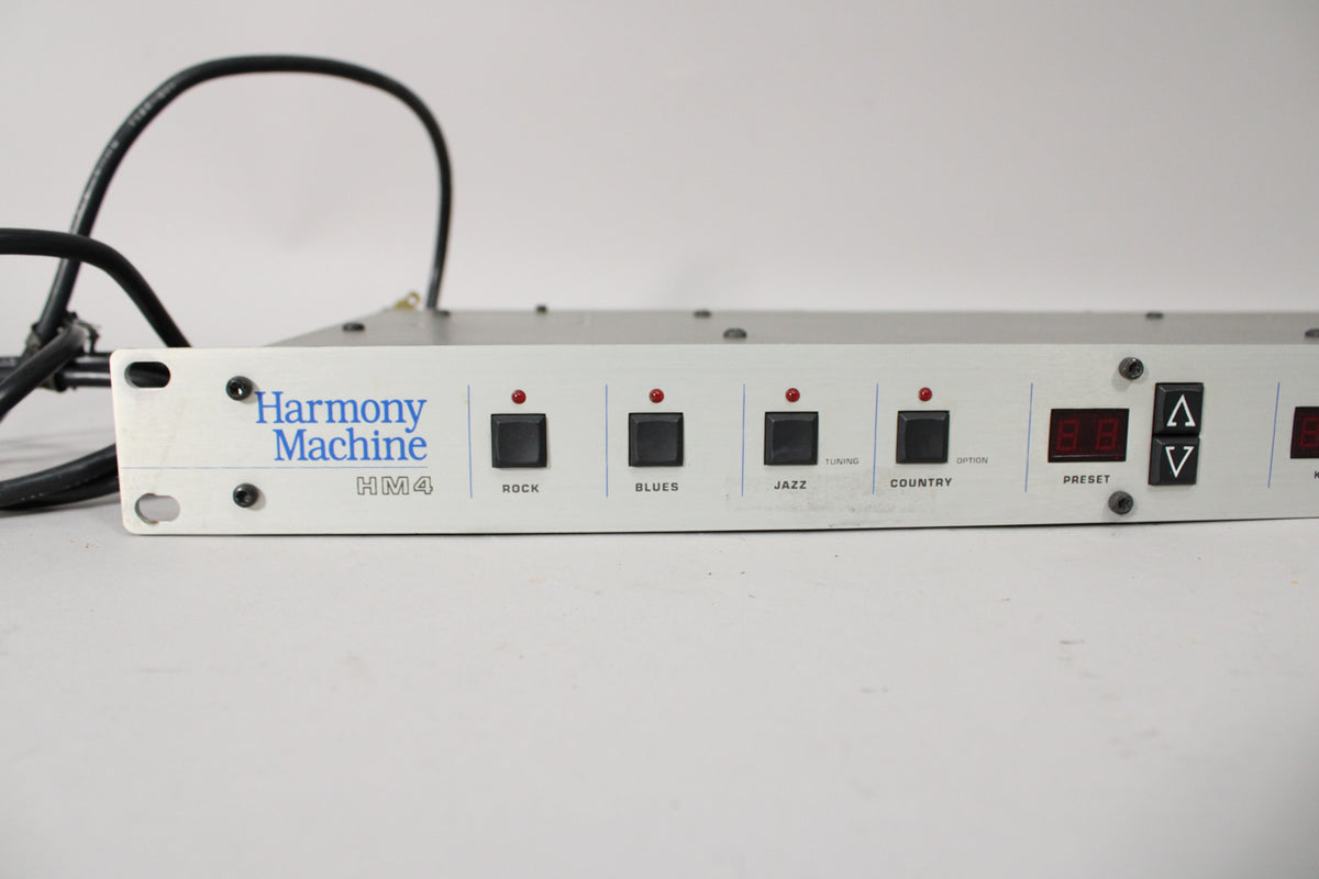 The silver rackmount unit's front panel is visible, showing black buttons for Rock, Blues, Jazz, Country, and a red digital display.