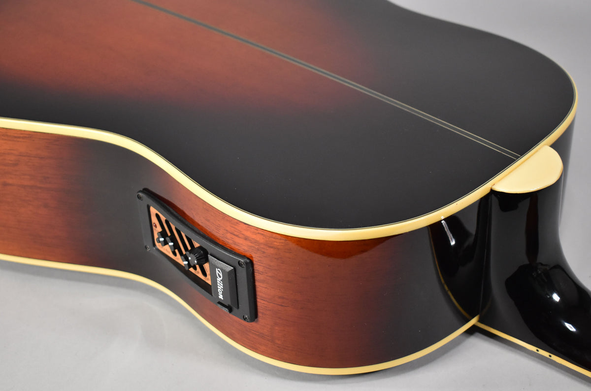 Close-up of the guitar's lower bout, showing the sunburst top, mahogany sides, cream binding, and black preamp with three sliders.