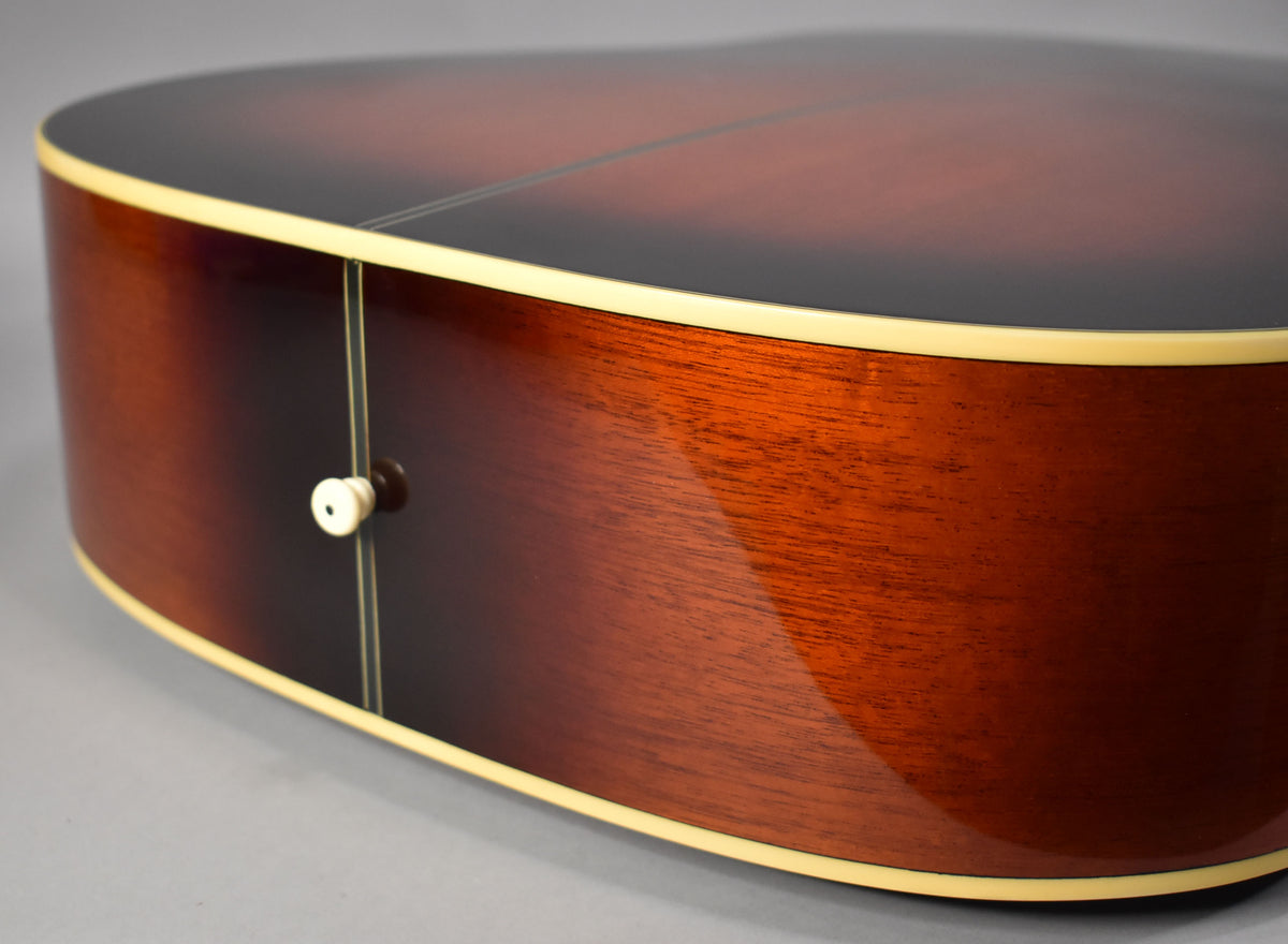 Close-up of the guitar's lower bout, showing the sunburst finish on the top and side, with a cream binding and endpin.