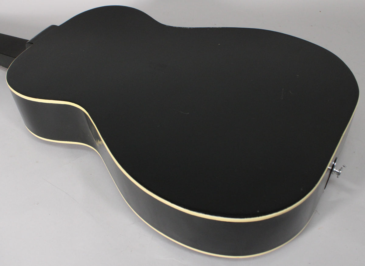 The black acoustic resonator's back and side are shown from above, revealing light wear and a chrome endpin jack.