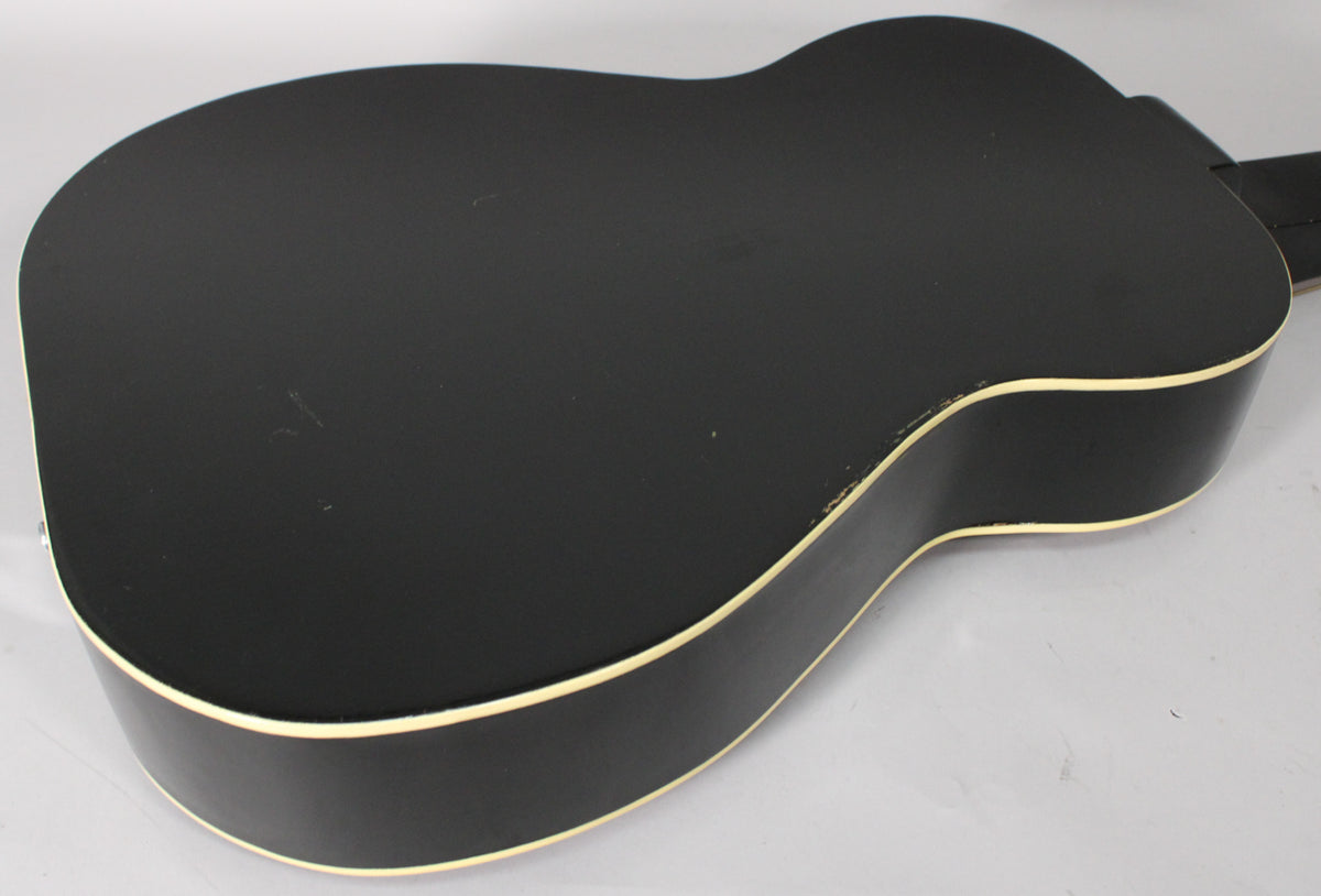The black resonator's back and side are visible, showing a matte finish, cream binding, and some light scratches and wear.