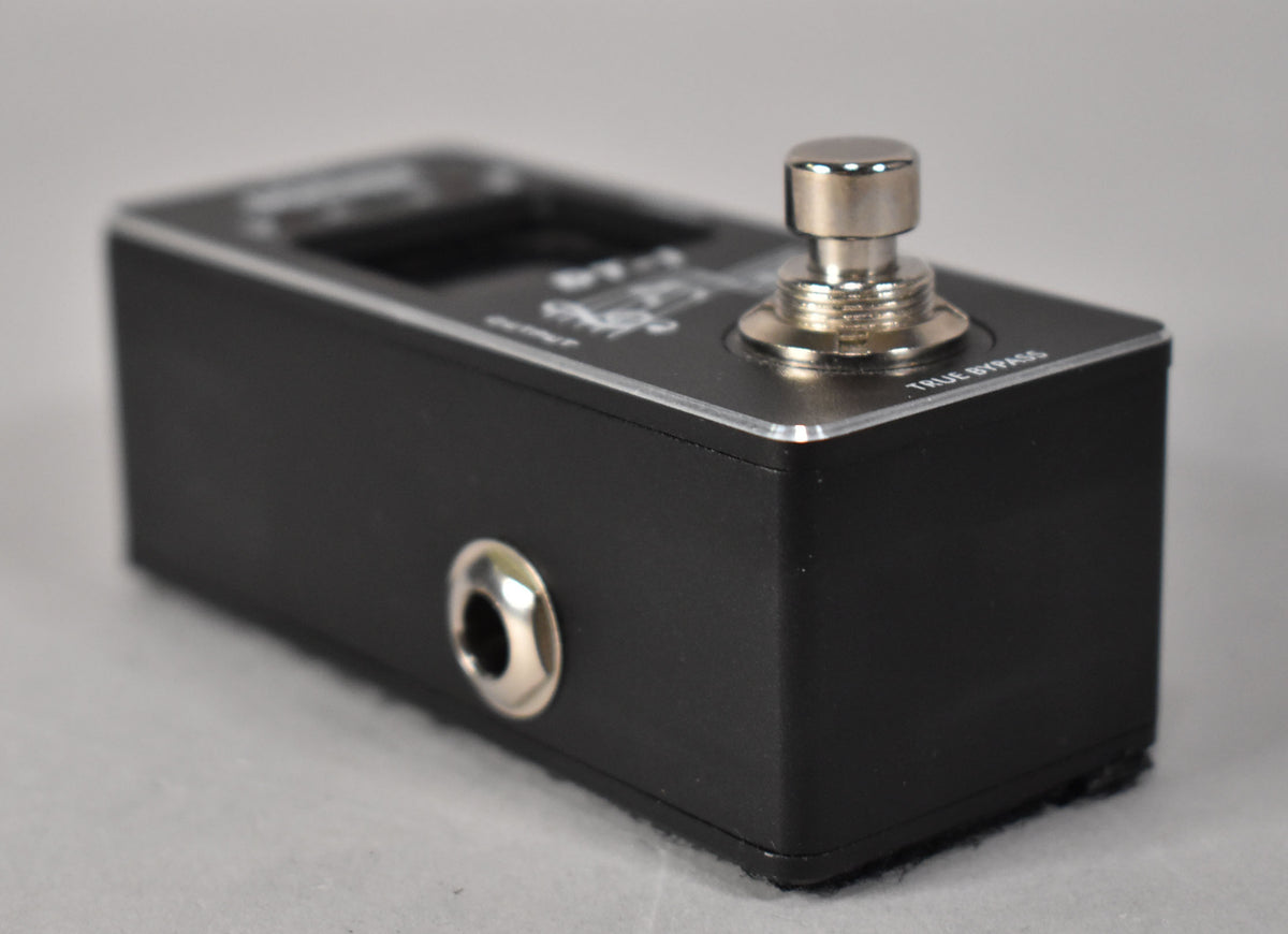 Close-up of the black pedal's right side, showing a chrome footswitch, a silver 1/4" jack, and a silver top edge.