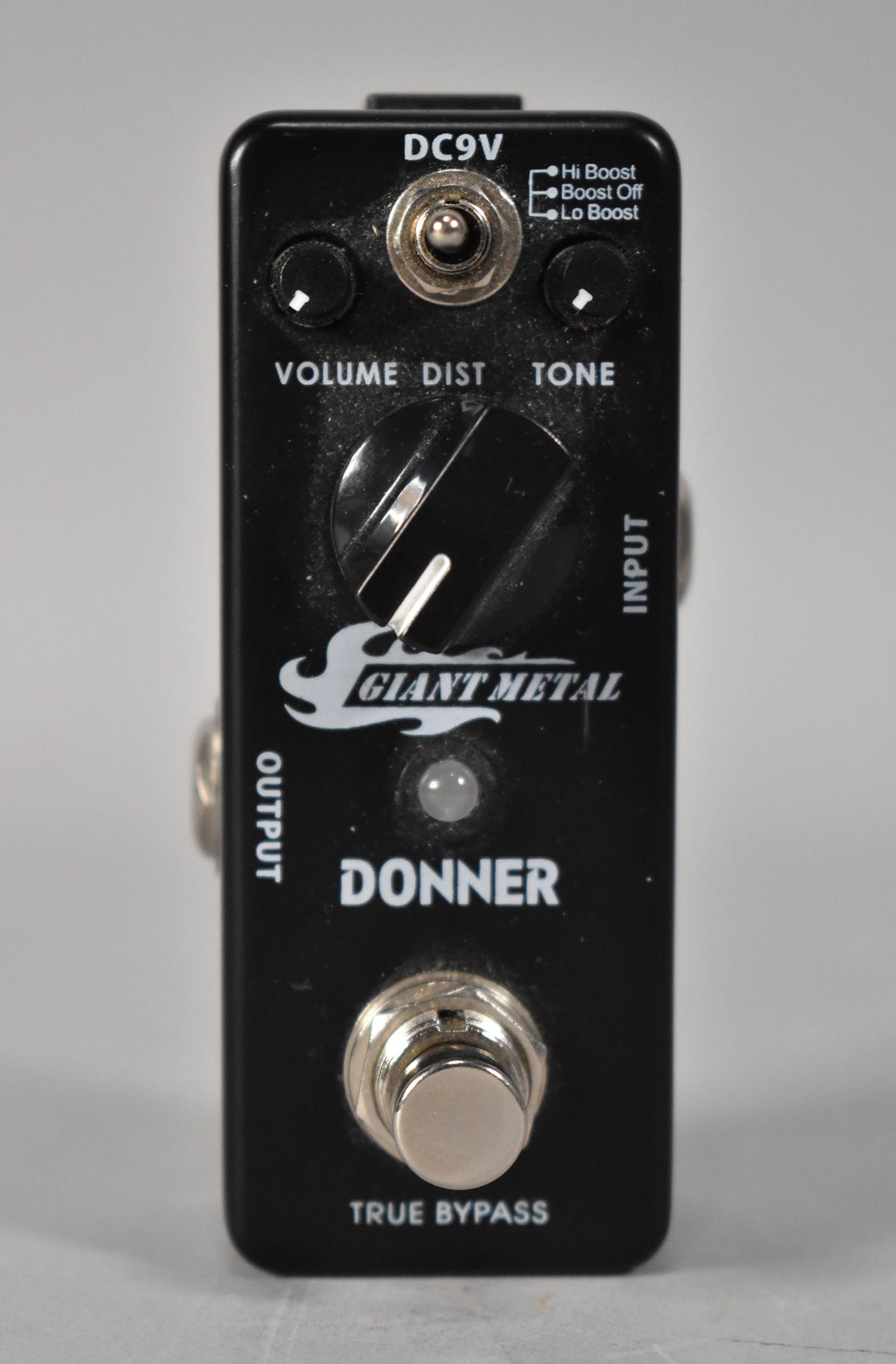 A black metal distortion pedal with three small knobs, a large central knob, a toggle switch, and a footswitch.