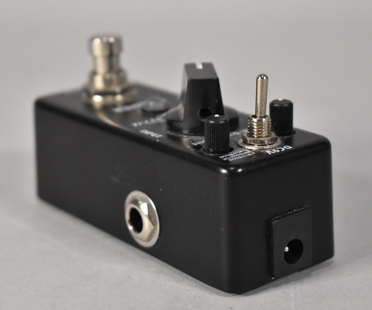 A black metal distortion pedal, angled to show the input jack, power input, and a metal toggle switch.