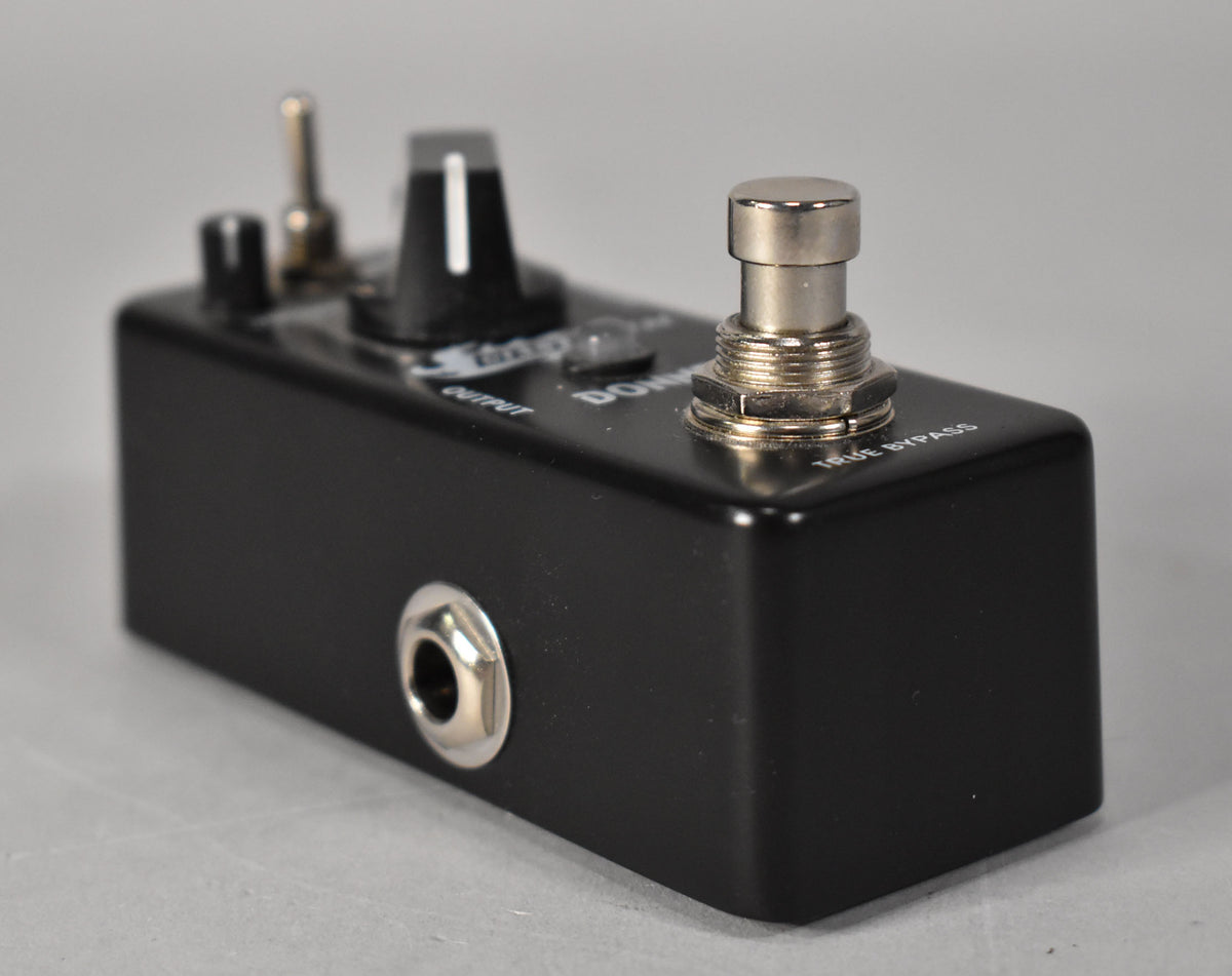 Black metal effect pedal, angled from the left, showing the output jack, a large black knob, a toggle switch, and a silver footswitch.