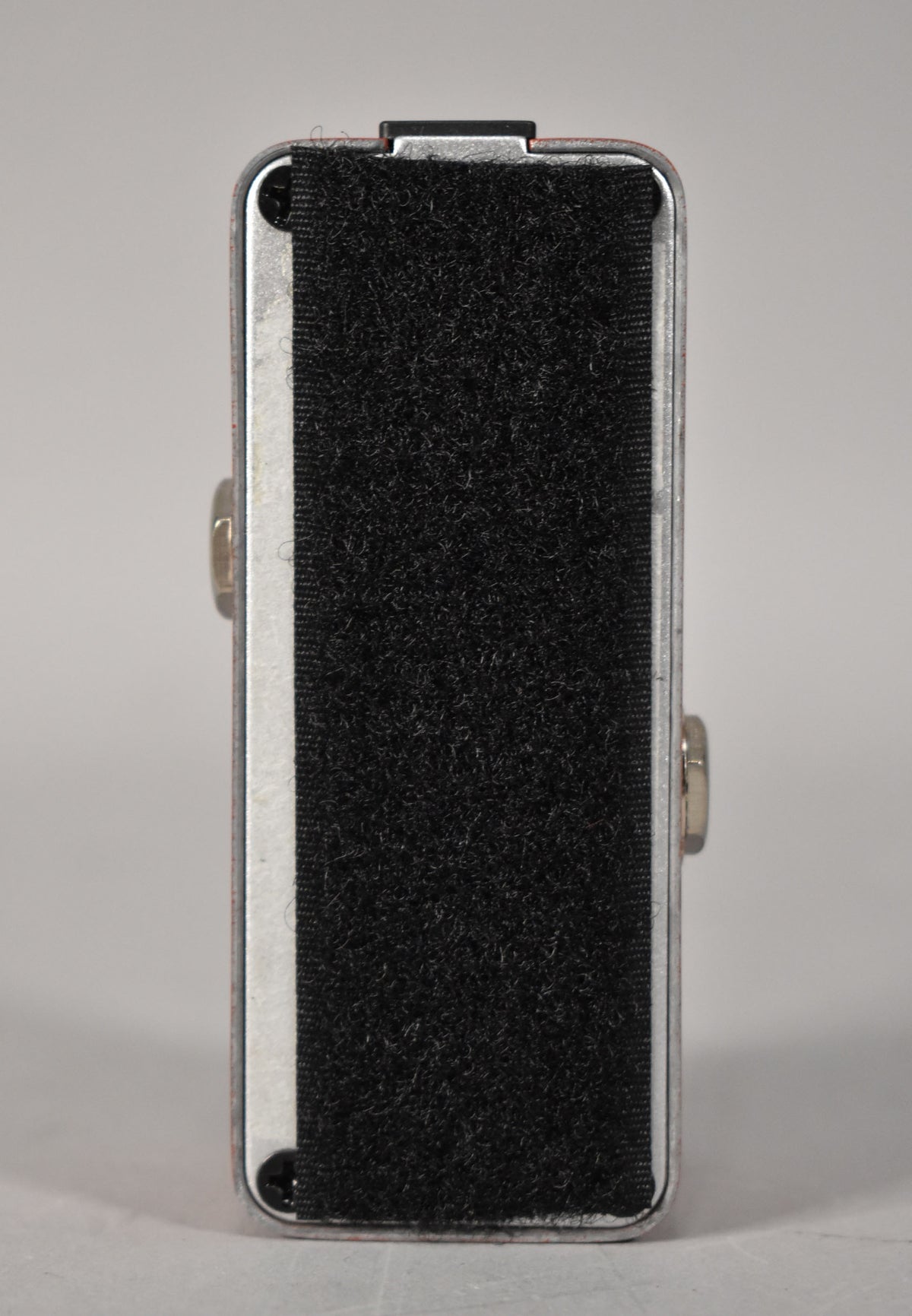 The pedal's bottom is covered in black hook-and-loop tape, with silver sides showing light wear and two visible screws.